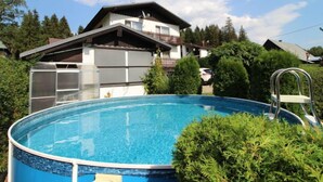 Ein Wohngebiet mit Schwimmbad, einem zweigeschossigen Haus mit Balkon und umgebender Bepflanzung.