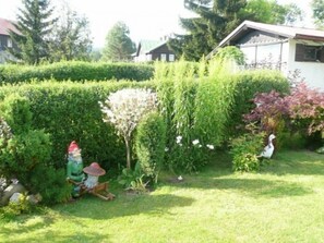 Un jardín bien cuidado con seto, comedero para pájaros y una estatua de una persona.