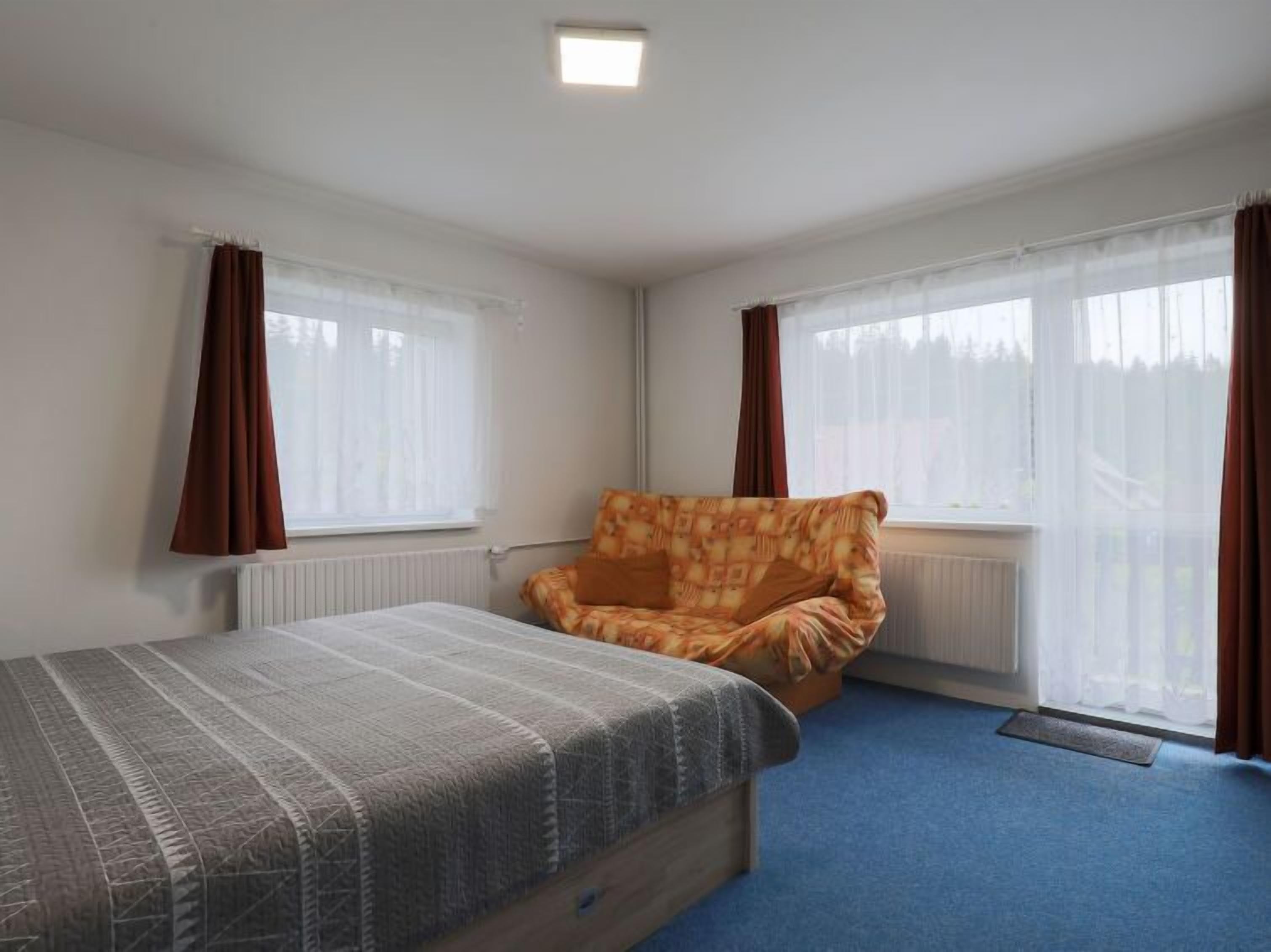 Une chambre à coucher avec un lit, un canapé et deux fenêtres avec des rideaux.