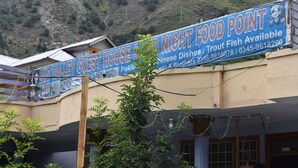 Cartel que anuncia una casa de huéspedes y restaurante, con servicios como trucha y platos chinos.