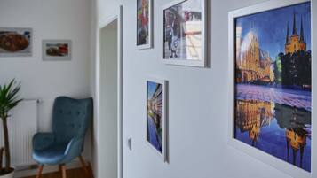 Relax in a serene space with a blue armchair, potted plant, and framed photographs on the wall.