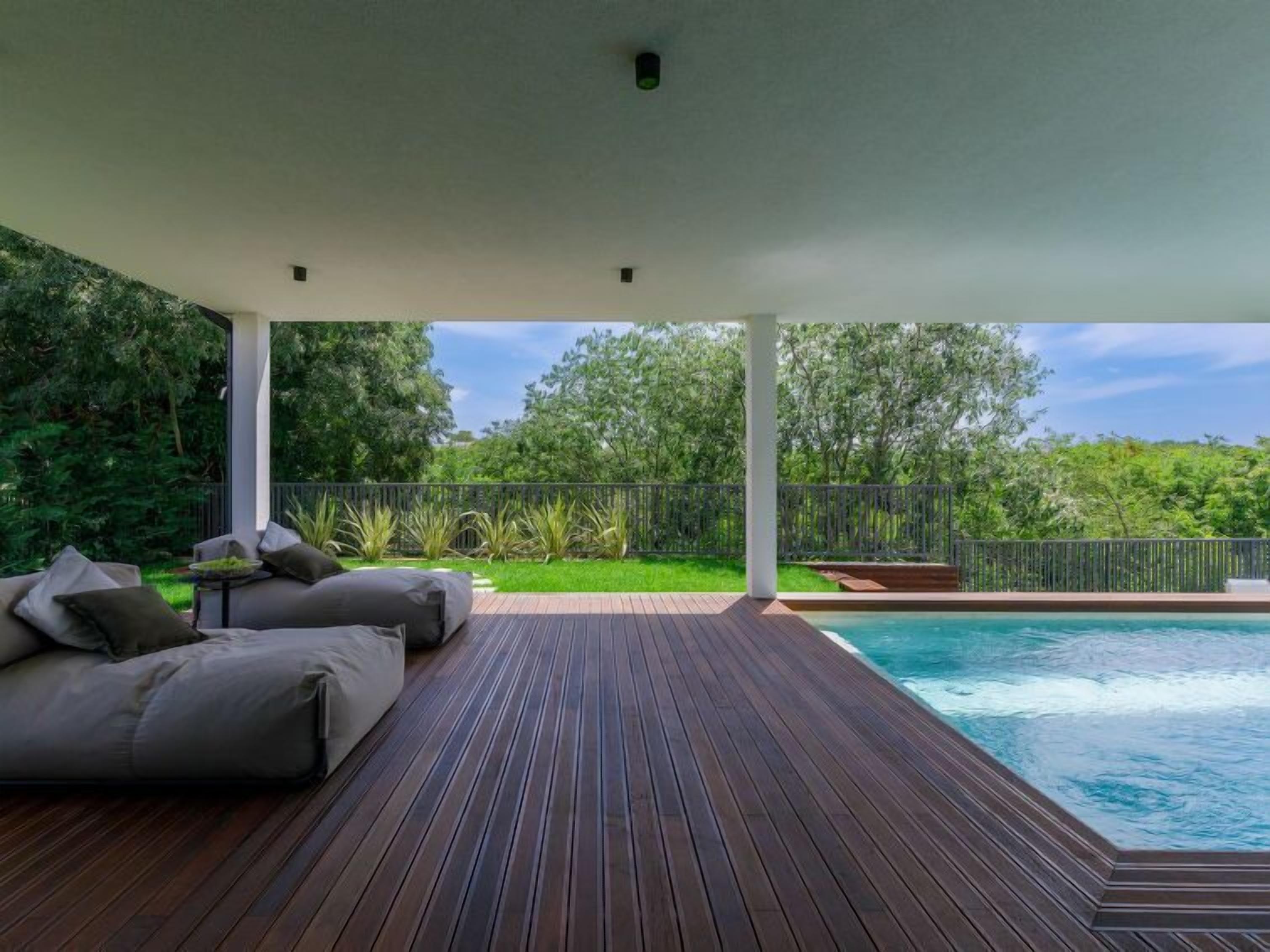 Une terrasse en bois avec une piscine, un espace salon extérieur et une vue sur la verdure.