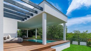 A modern outdoor deck with a pool, wooden steps, and a covered seating area with cushions. - Villa Valle by Interhome (Rovinj/Bale)