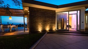 A modern house with a patio, a dining area, and a large glass door leading inside. - Villa Atmosfere 8 in Frassi (Arce)