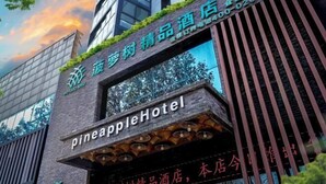 Un hotel con fachada moderna, que presenta un letrero llamativo que dice "pineappleHotel".