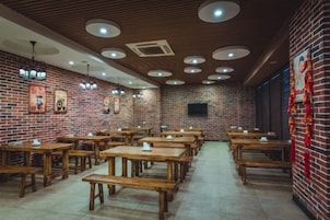 A restaurant with brick walls, wooden tables, and ceiling lights.