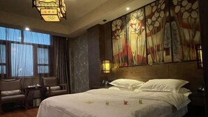 Habitación de hotel con una cama grande, un sofá, una mesita y un cuadro en la pared.