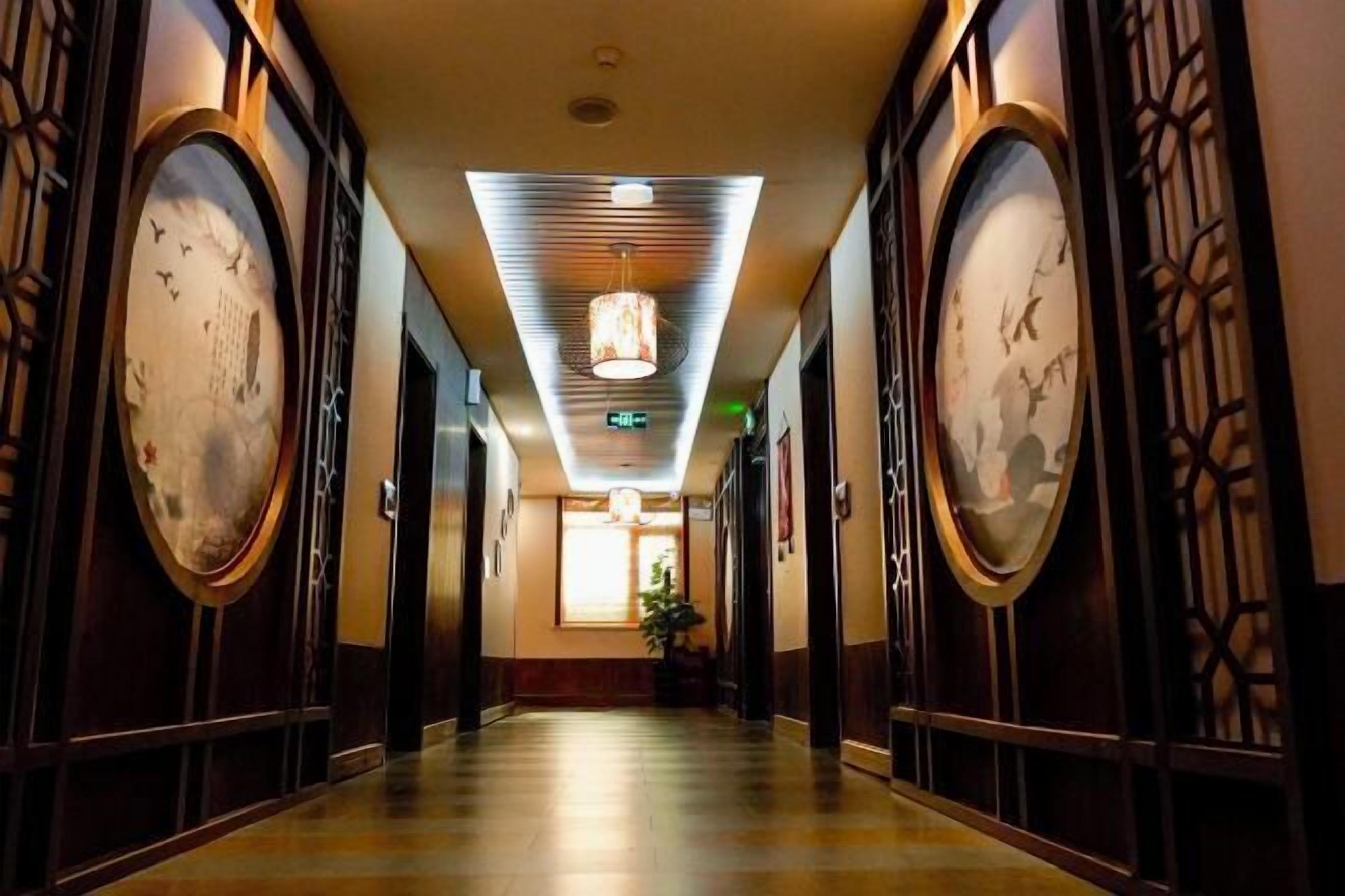 A corridor with traditional decor, including wooden doors and framed artwork on the walls.