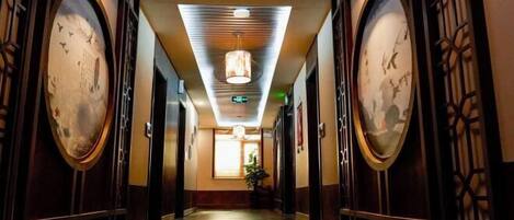 A corridor with traditional decor, including wooden doors and framed artwork on the walls.