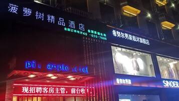 A hotel with a neon sign for 'Piu Apple Hotel' and another sign for 'Sinoer'.
