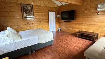 Een kamer met houten lambrisering, een bed, een bankje en een televisie.