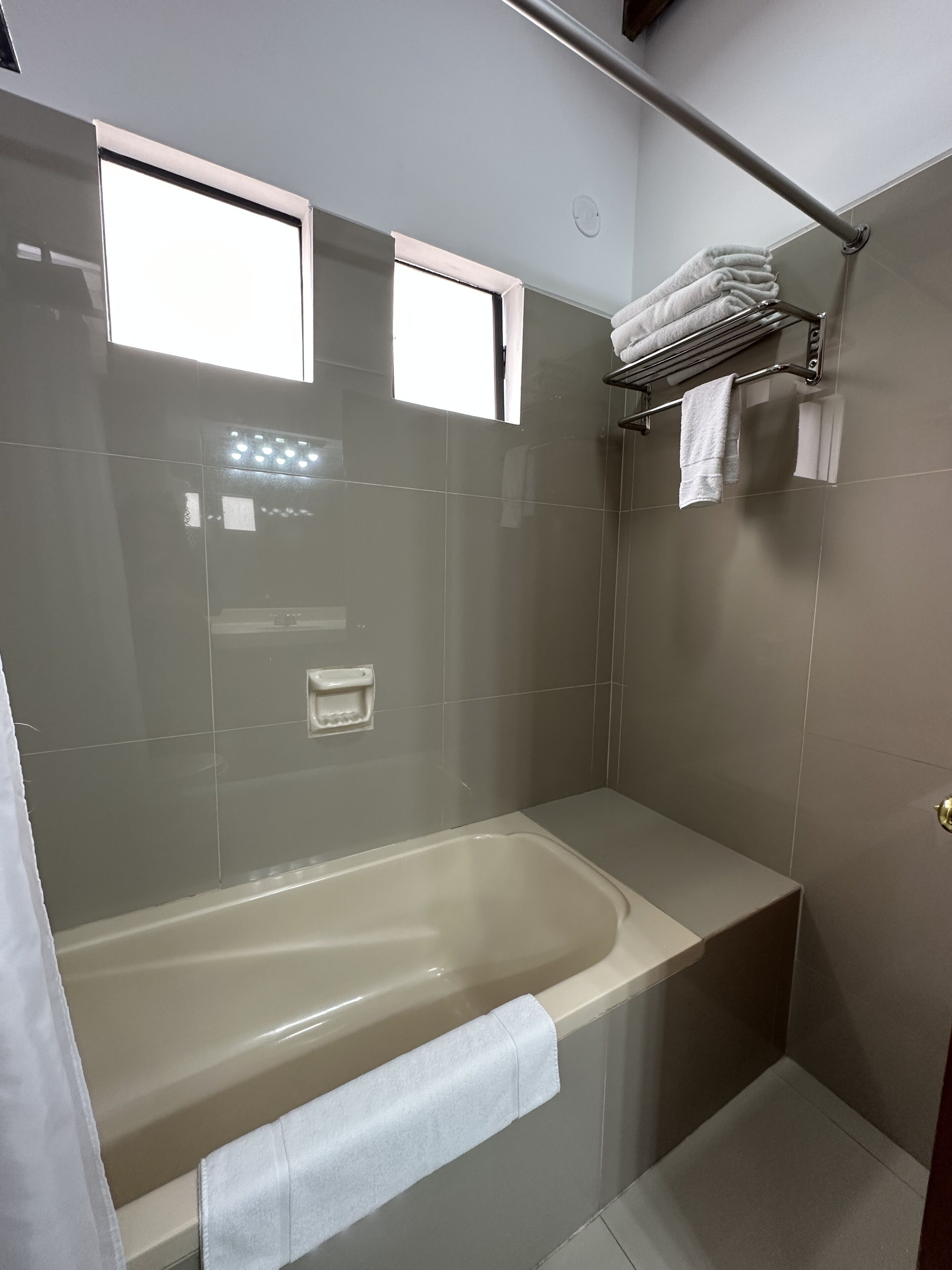 A modern bathroom with a bathtub, a towel rack, and a window.