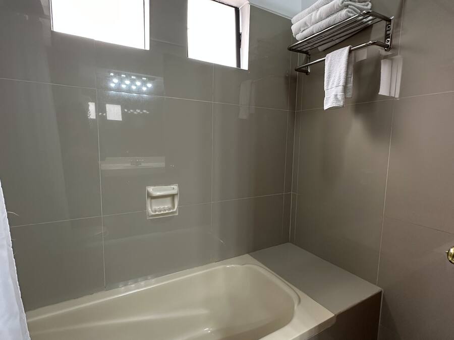 A modern bathroom with a bathtub, a towel rack, and a window.