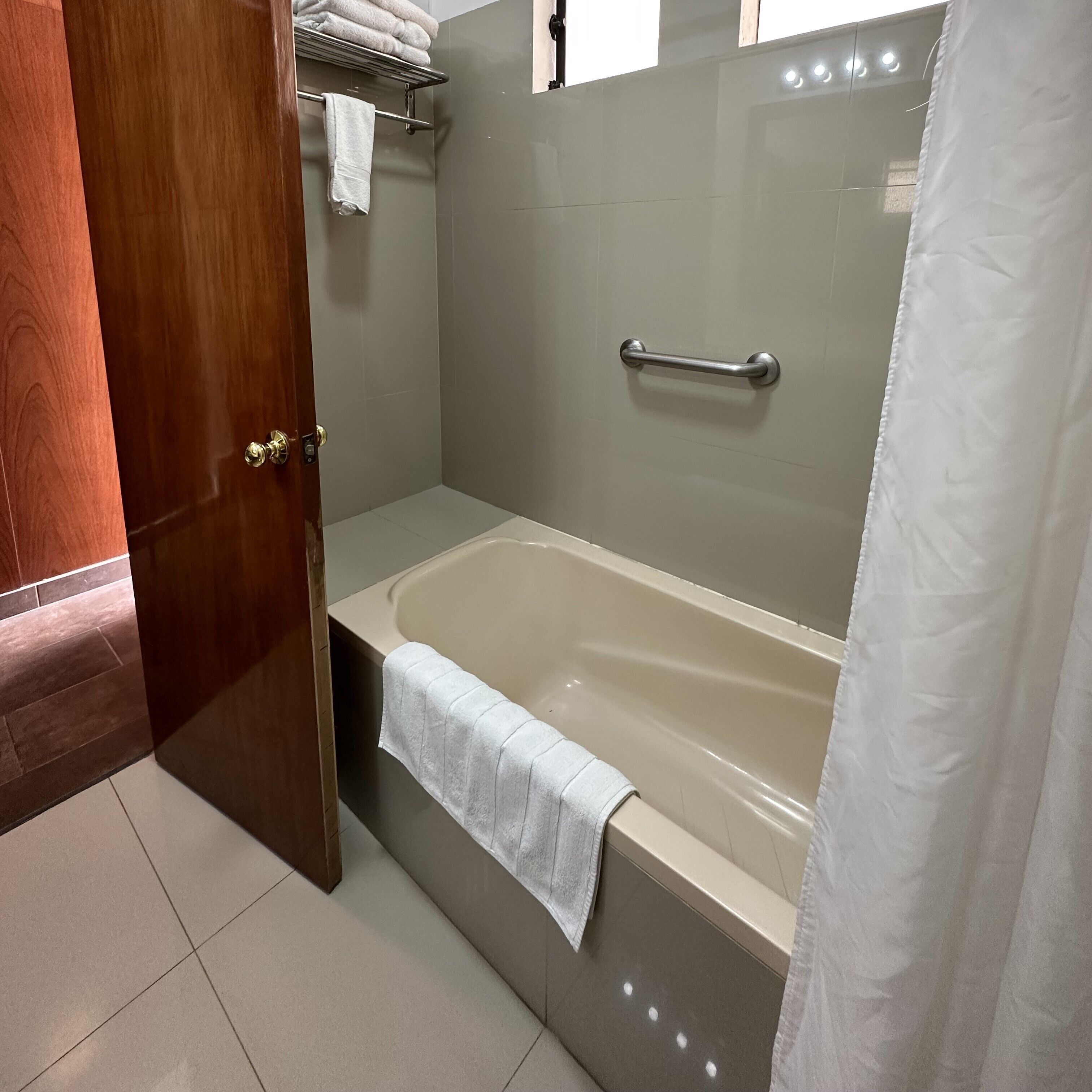 A bathroom with a bathtub, a towel rack, and a shower curtain.