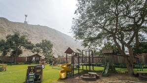 Un parque infantil con tobogán, estructuras para escalar y un arenero.