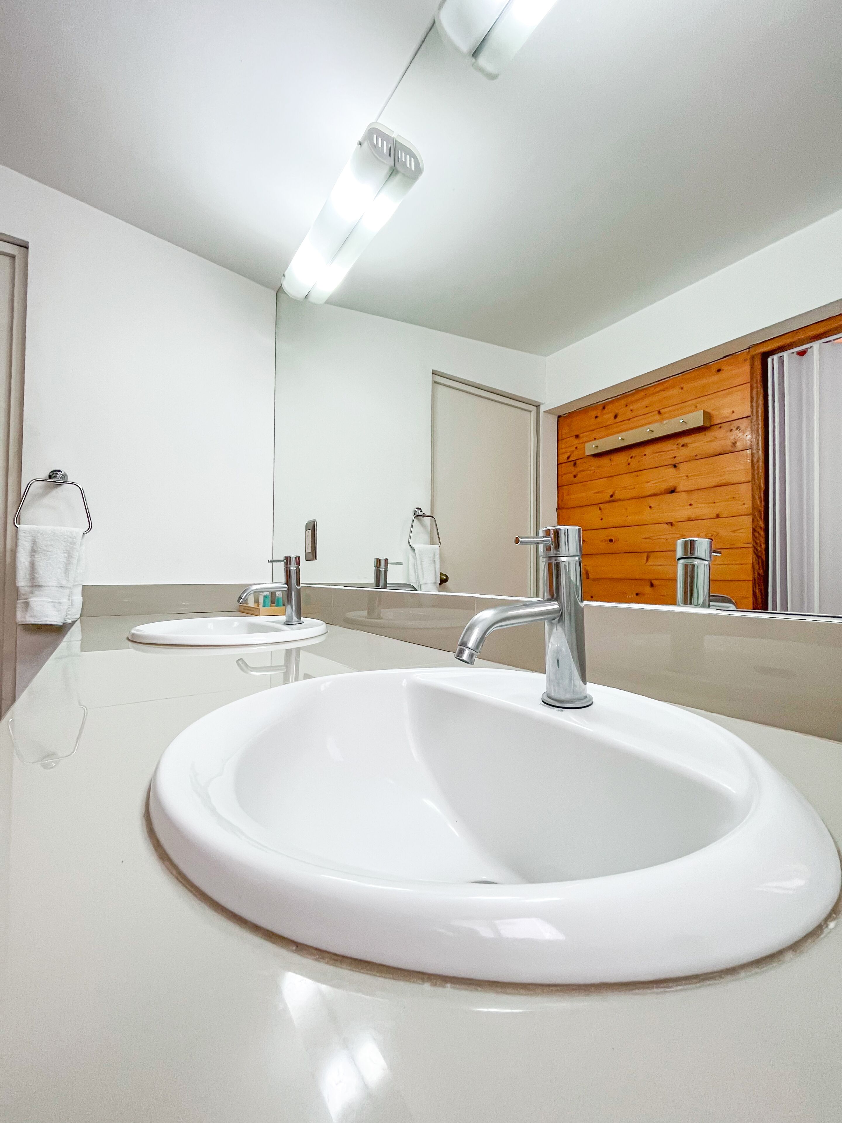 Un baño moderno con un lavabo blanco, un espejo y una pared de madera.
