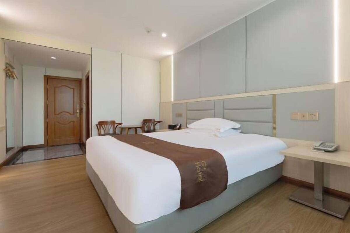 A hotel room with a bed, bedside table, and a mirror.