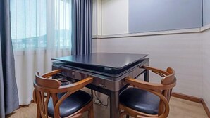 A room with a table and two chairs, a window with curtains, and a wall with a panel. - Q+ Shicheng Zuguoshun Hotel (Shicheng County Bus Station) (Shicheng)
