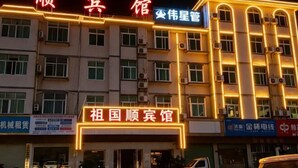 A hotel with multiple floors, illuminated signage, and a variety of shops on the ground level. - Q+ Shicheng Zuguoshun Hotel (Shicheng County Bus Station) (Shicheng)
