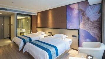 A hotel room with two beds, a large mirror, a wall mural, and a seating area.