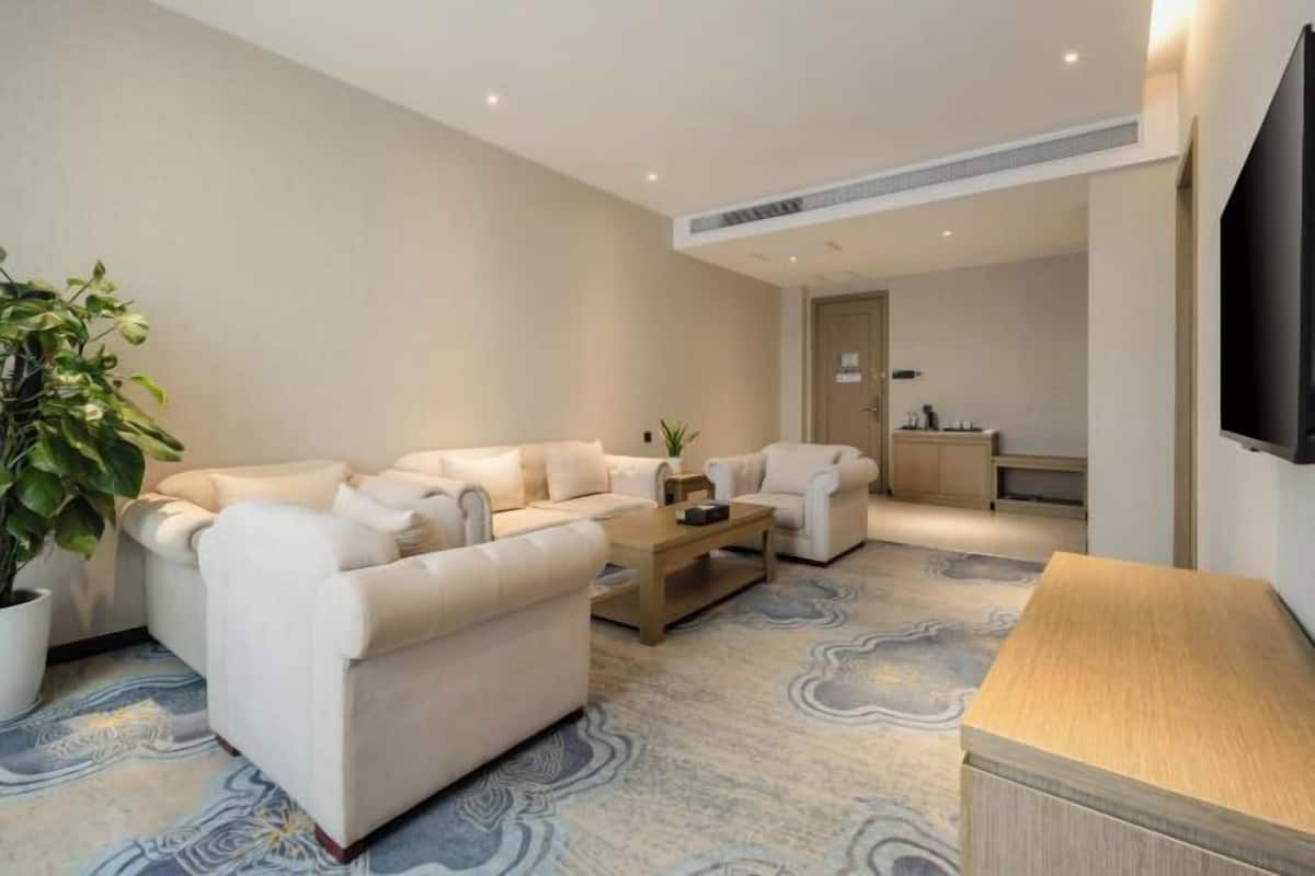 A modern living room with a sofa set, a coffee table, and a TV mounted on the wall.