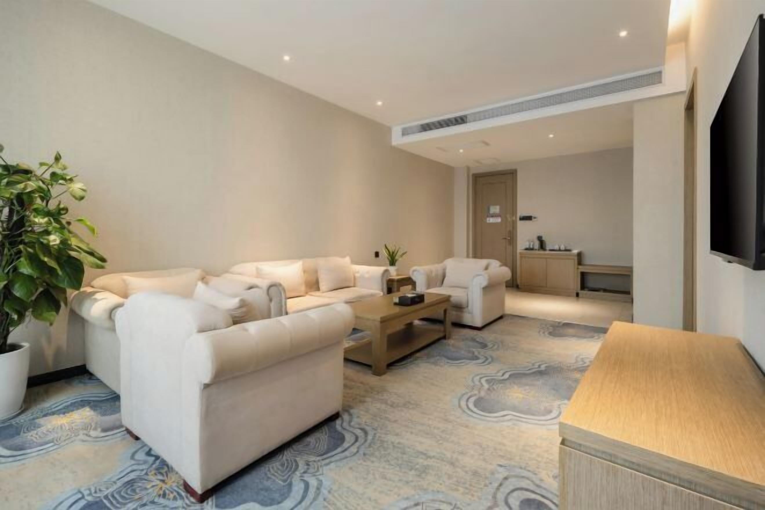 A modern living room with a sofa set, a coffee table, and a TV mounted on the wall.