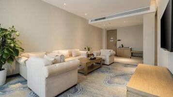 A modern living room with a sofa set, a coffee table, and a TV mounted on the wall.