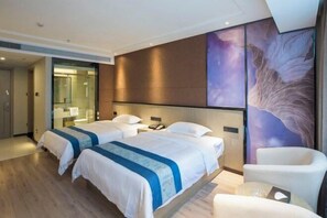 A hotel room with two beds, a large wall mural, and a seating area. - Sanfeng Hotel (Nanning)