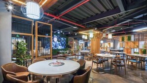 A modern interior with a round table and chairs, a television screen, and shelves with plants. - Sanfeng Hotel (Nanning)