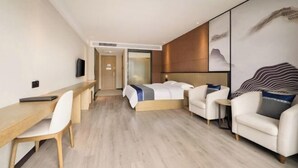 A modern hotel room with a bed, two armchairs, a desk, and a large wall mural. - Sanfeng Hotel (Nanning)