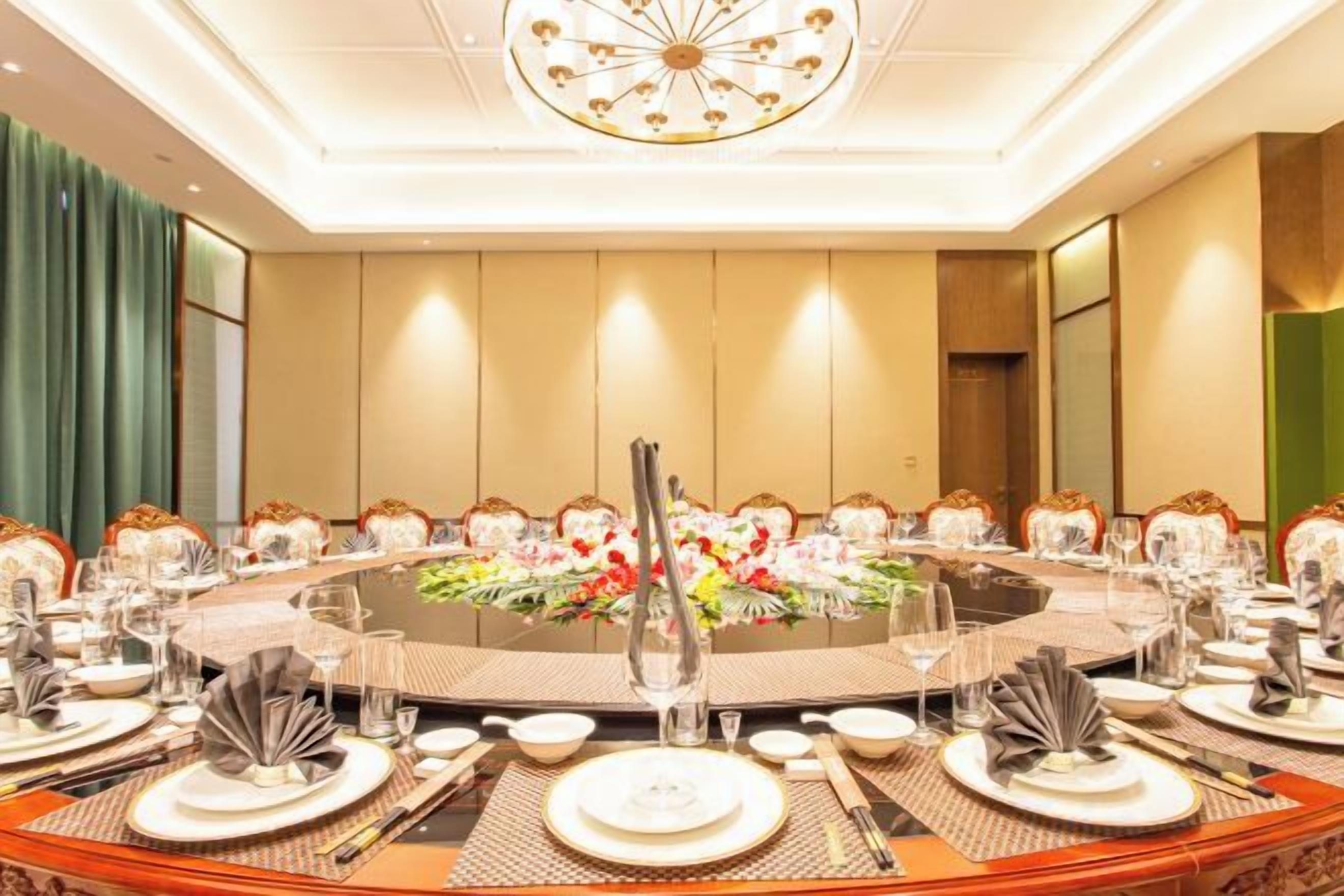 Une salle de conférence avec une table ronde, des chaises et un lustre.