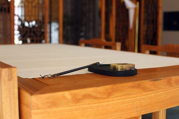 A wooden table with a cork coaster and a black object on it.