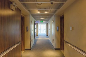 A hotel corridor with doors on both sides, a carpeted floor, and a ceiling with a smoke detector. - The Elms lnn(Zhuhai BNBU) (Zhuhai)