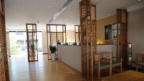 Un área de recepción con un mostrador de madera, varias sillas y una planta en maceta.