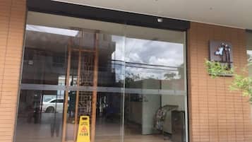 A building entrance with a large glass door, a wooden floor inside, and a caution sign outside.