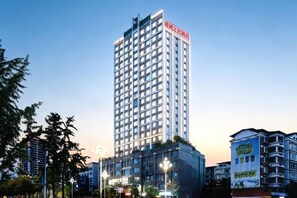 A high-rise hotel with multiple floors, surrounded by other buildings and trees. - Chongqing Tongcheng Zhiguang Hotel (Tongnan Branch) (Chongqing)