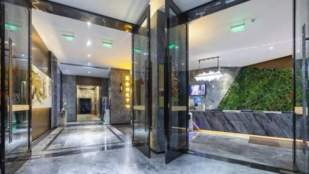 A modern hotel lobby with glass doors, a marble floor, and a green wall. - Chongqing Tongcheng Zhiguang Hotel (Tongnan Branch) (Chongqing)