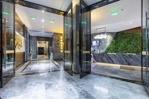 A modern hotel lobby with glass doors, a marble floor, and a green wall. - Chongqing Tongcheng Zhiguang Hotel (Tongnan Branch) (Chongqing)