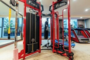 A gym with red equipment, a punching bag, and treadmills.