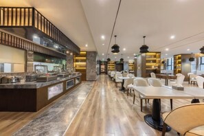 A modern restaurant with a long counter, dining tables, and a kitchen area. - Chongqing Tongcheng Zhiguang Hotel (Tongnan Branch) (Chongqing)