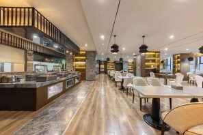 A modern restaurant with a long counter, seating area, and a kitchen visible in the background. - Chongqing Tongcheng Zhiguang Hotel (Tongnan Branch) (Chongqing)