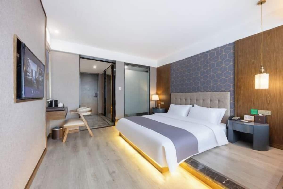 A hotel room with a large bed, bedside tables, a desk, and a chair.