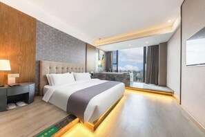 Moderni hotellihuone, jossa on suuri sänky, yöpöytä, näköala kaupunkiin ja parveke.