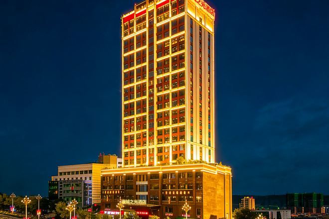 Un hotel de gran altura con varios pisos, ventanas iluminadas y una entrada destacada en la base.