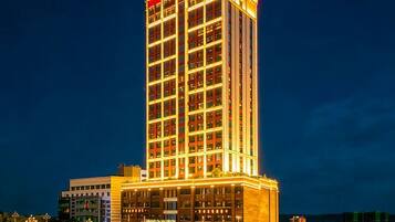 A high-rise hotel with multiple floors, illuminated windows, and a prominent entrance at the base.