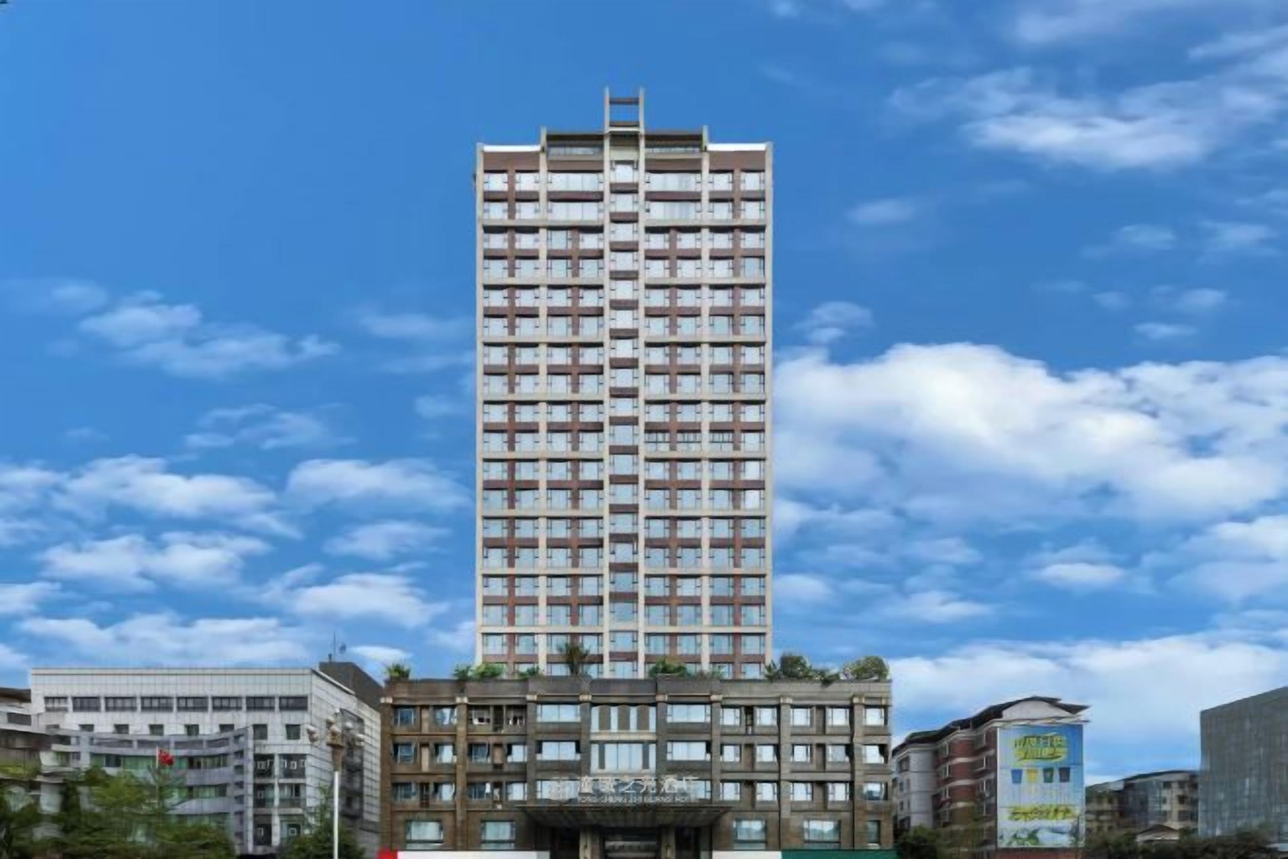 Een hoog gebouw met meerdere verdiepingen, een centrale ingang en omliggende kleinere gebouwen.