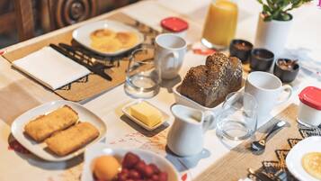 Une table de petit-déjeuner avec des assiettes remplies de nourriture, une carafe de lait et un verre de jus d’orange.