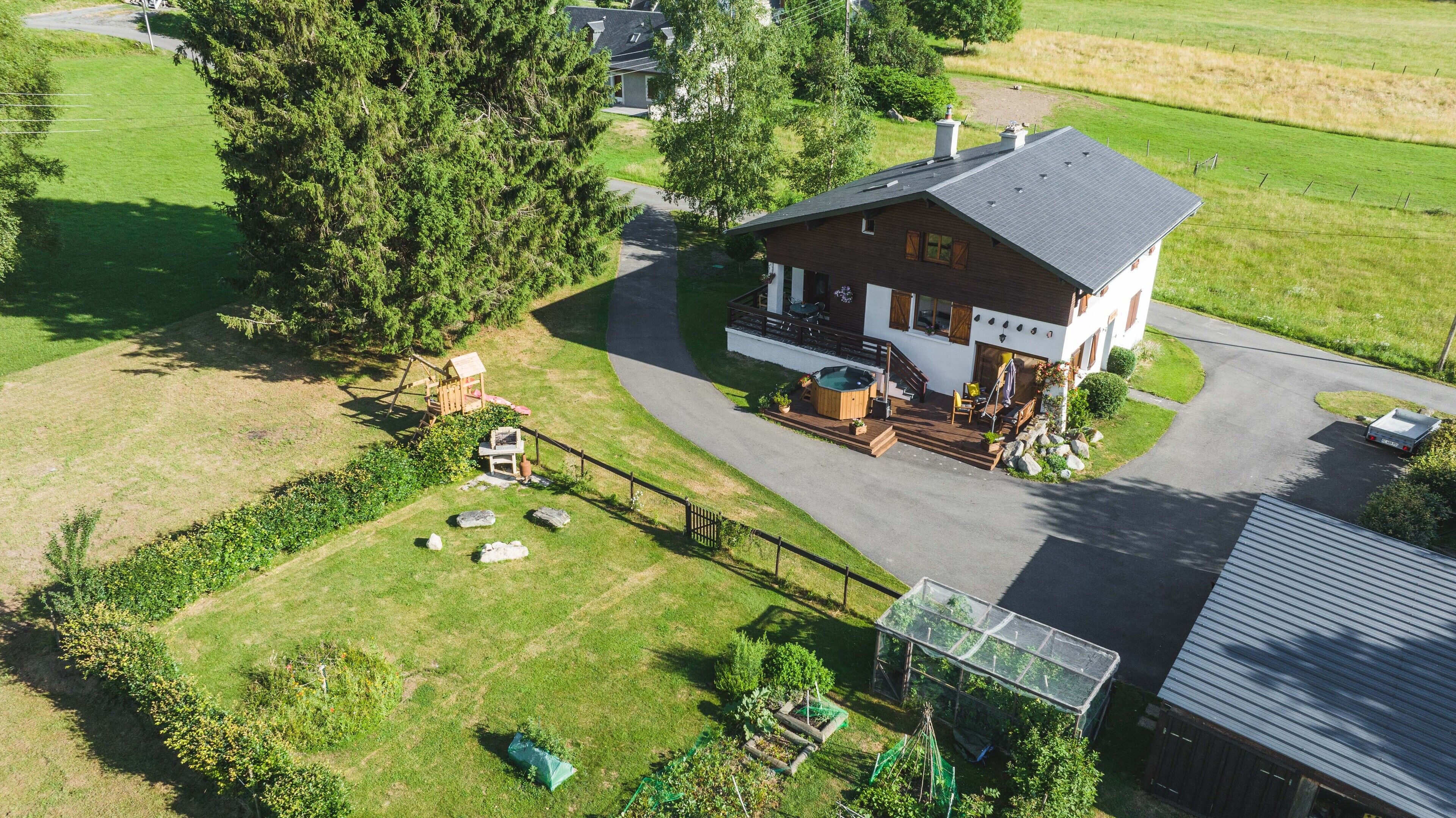 A two-story house with a patio, a hot tub, and a greenhouse.