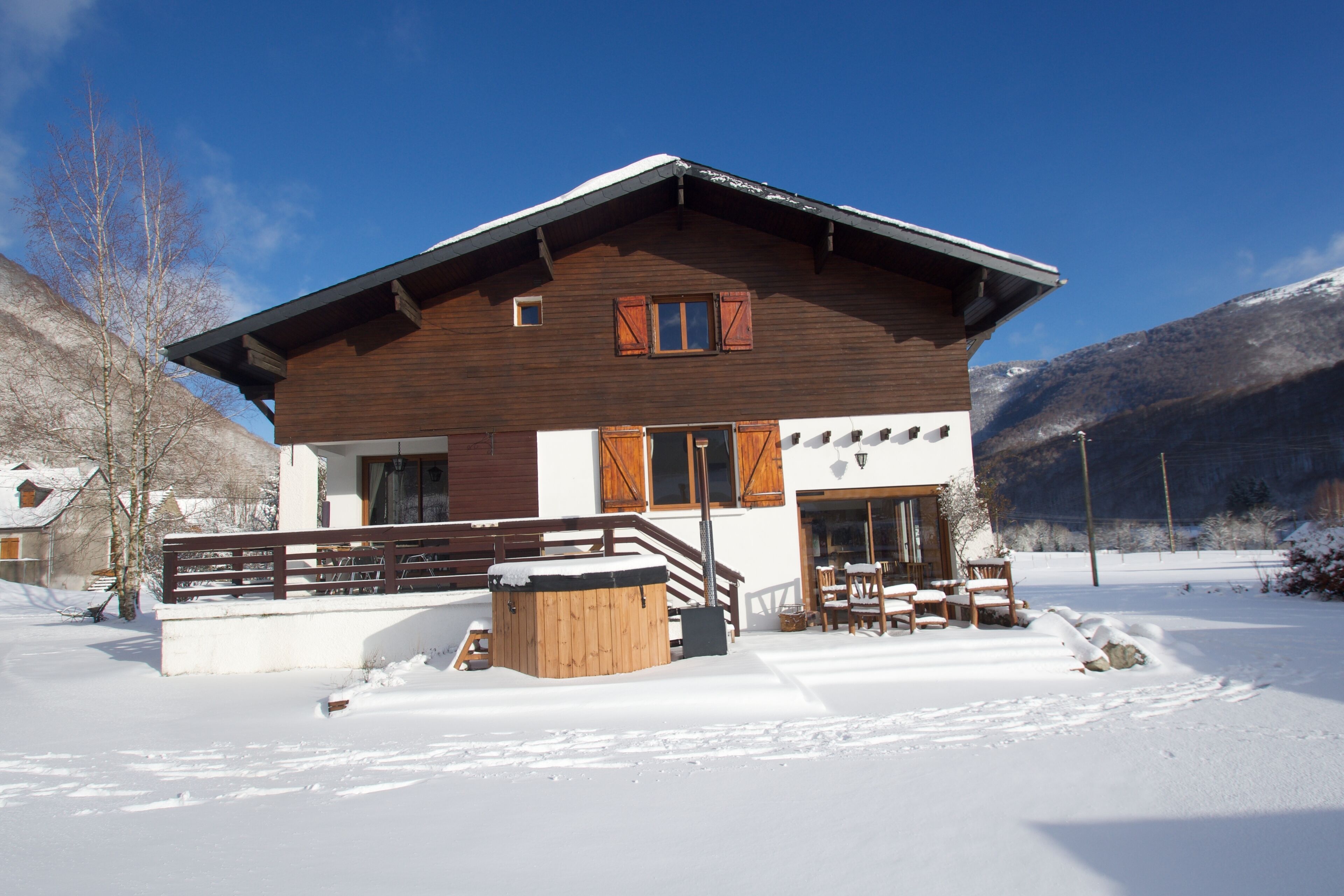 Eine Holzhütte mit Balkon, Whirlpool und Sitzgelegenheit im Freien.