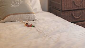 A neatly made bed with a decorative pillow and a small gift box, a bedside lamp, and a framed picture on the wall.